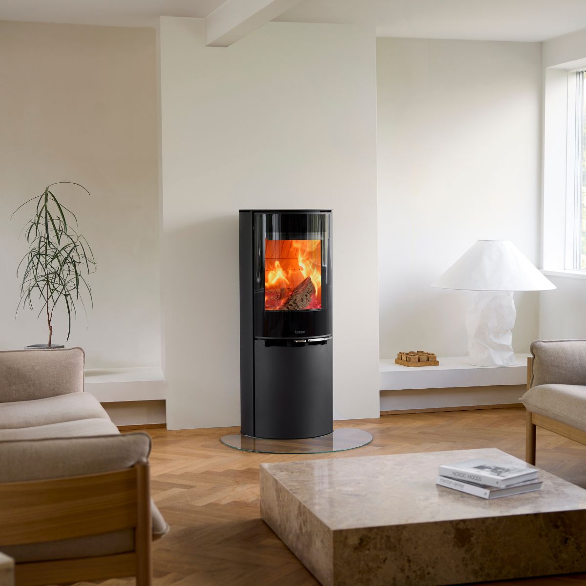 Rund, høj brændeovn med glasfront brænder i moderne hjem